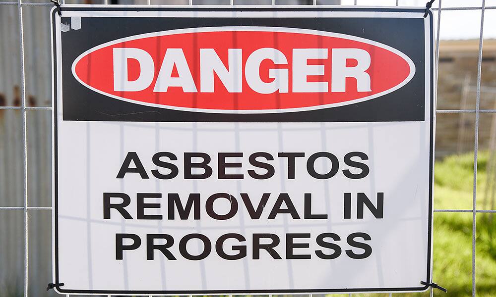 Danger asbestos removal in progress sign at a demolition site