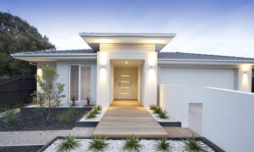 Paved entry path and masonry garden walls leading to a modern home